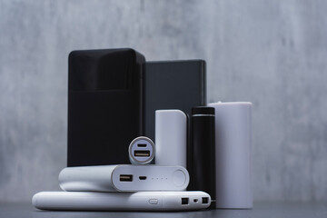 A group of power banks in various shapes, sizes, and colors on a table. Concept portable charging solutions, mobile technology, and on-the-go energy backup for smartphones and devices.