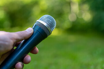 The microphone is in the hands of the presenter.Outdoor studio in the fresh air.An open-air concert.