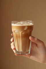 Photorealistic female hand holding a glass of iced coffee, minimal style, on beige background