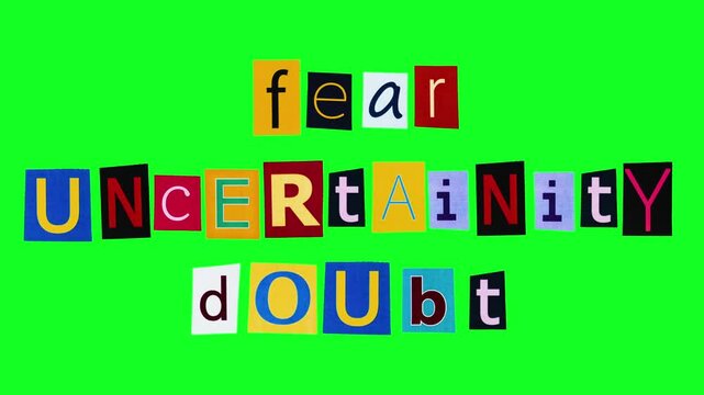 Fear uncertainty and doubt slogan made of colorful sticker with printed letter moving on chroma key. Isolated banner with manipulative propaganda used in sales of cryptocurrency filmed in green screen