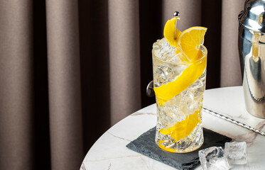 Refreshing horse neck cocktail with bourbon and ginger ale garnished with lemon on a chic marble...