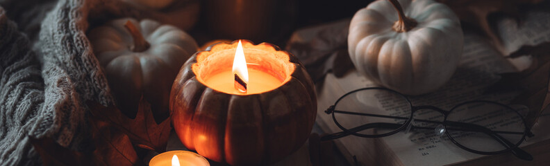 Cozy autumn home still life scene. Ceramic handmade pumpkin mug with burning candle near the...