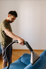 Vertical portrait of cleaning service worker using washing vacuum cleaner to remove dirt and stains...