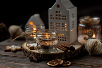 Creating holiday mood, festive atmosphere at home. Christmas spirit, atmospheric composition with handmade aroma candles made from simple glass jars, homemade gingerbread cookies, anise cinnamon scent