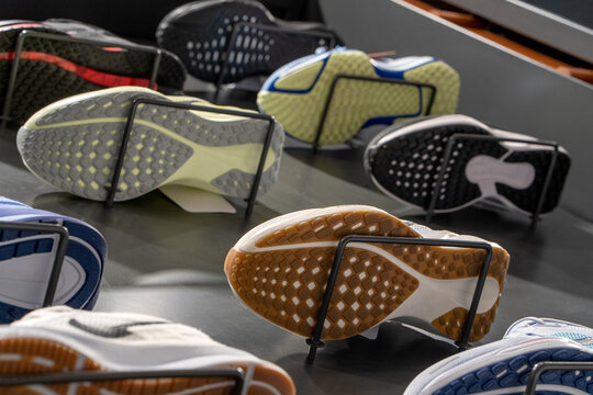 Bottom view of the store window with a modern new sneakers running shoes on the wall. Soles of sports shoes.