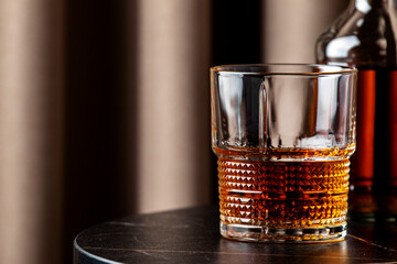 rich bourbon whiskey sits in textured glass on a modern table next to a bottle, showcasing a warm and inviting atmosphere.