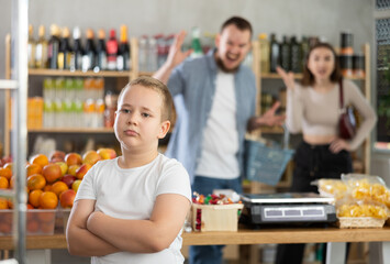 Angry couple young man and woman quarreling with son in grocery store