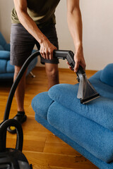 Close-up vertical cropped shot of cleaning service worker using washing vacuum cleaner to clean...