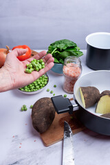 Taking green peas among other vegetables for cooking.