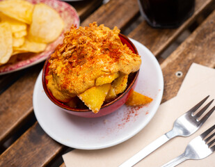Delicious baked potatoes with creamy garlic sauce aioli, crispy pork rinds and spicy paprika. Typical Spanish dish Patatas bravas