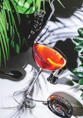 Hanky Panky cocktail with gin, vermouth, and herbal liqueur set against a lush green backdrop