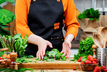 Cooking fresh vegan dishes with vibrant vegetables, chard and herbs in a modern kitchen environment