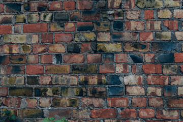 Old textured colorful brick wall with orange blue and pink details. Weathered, colored brick background.

