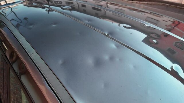 hail damaged car roof, showing visible dents on the metal surface under natural light.