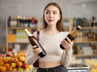 European girl took different varieties of beer from shelf, chooses beer light alcohol beverage....