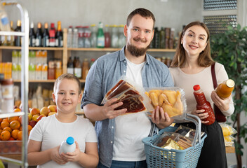 Couple young man and woman buyers with boy choosing food in grocery store