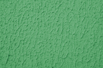 Close up of textured green color painted wall with rough stucco, plaster wall texture. Vibrant background, wallpaper, backdrop, design element.