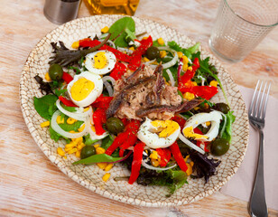 Spanish typical cuisine, salad with tuna fish, arugula, boiled eggs, corn and pepper in a cafe