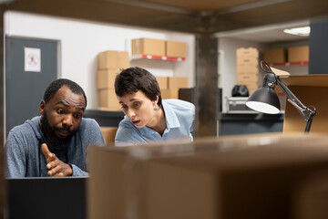 Diverse team at desk discussing order processing to guarantee distribution in a tightly packed...