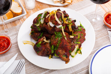 Delicious pork shashlik with adzhika sauce and sliced onion rings on a plate in a restaurant