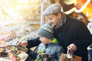 Father and son visited a Christmas market and look at the figurines to create a nativity scene.
