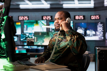 Military officer collaborating with general on telephone call to deploy electronic warfare tools...