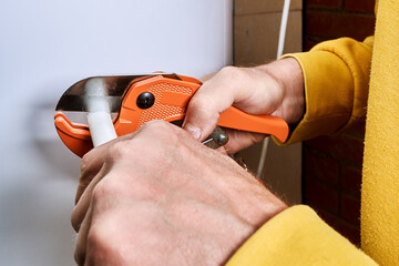 Ratchet pipe cutter slices multilayer pipe as hands operate tool during pipe cutting process for...