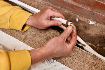 Installation process shows technician fitting compression ring to composite tubing before connecting water supply lines using compression fitting for plumbing work.