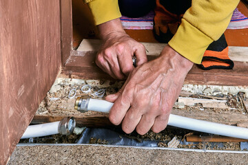 Plumber uses hands to connect multilayer pipe with compression fitting, working on plumbing system...