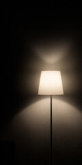 A floor lamp turned on near a wall in a dark room. Warm light creates soft shadows and a cozy ambiance. Minimalist interior in Scandinavian style.