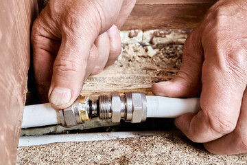Plumber installs compression coupling to connect two sections of multilayer pipe previously cut at...