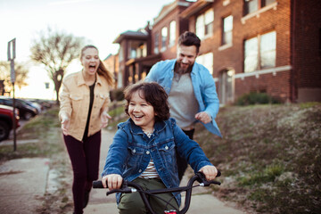 Parents teaching young son how to ride a bike outside