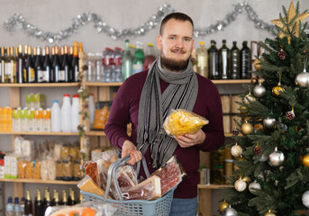Attentive boy choosing potato chips in a grocery store with Christmas decoration