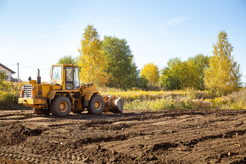 Yellow bulldozer at a construction site. Big wheel excavator leveling and clearing the land plot...