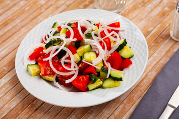 Healthy vegetable salad of sliced fresh tomatoes, cucumber and onion with olive oil