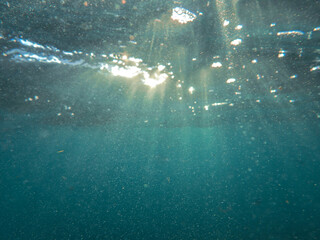 Ocean blue underwater with sunrays, Underwater Sea Deep Water Abstract Sunshine, sea wave , clean waters in summer time, Natural underwater seascape, sand on ocean floor and water surface with sunligh