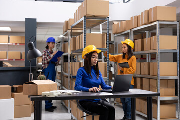 Asian staff member in a local brand supply room prepares products and taped boxes for shipment....