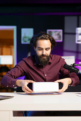 Tech content creator filming packaged product unboxing, giving reasons to purchase it. Influencer...