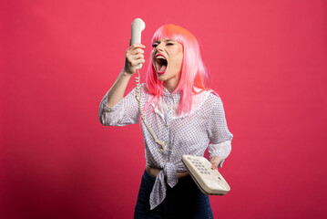 Furious young woman shouting into landline receiver. Angry caucasian lady yells at corded...