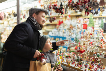 Father and son stand at the counter and choose figures for the Christmas nativity scene. Visitors...