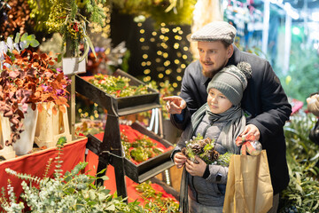 Father and son choose flowers, plants and branches for a winter flower arrangement and home decoration for Christmas. Son and dad visited the New Year's Fair outdoors