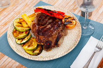 Appetizing spicy baked veal chop with side dish of potatoes and vegetables..