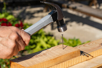 Worker using a hammer an metal nail into a wooden board, closeup. Hand tool for working....