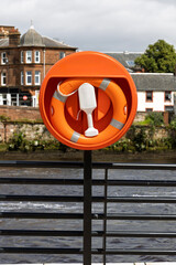 Riverside Safety: Orange Lifebuoy in Housing on Railings