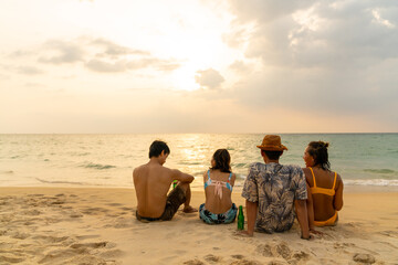 Happy Asian man and woman travel the sea drinking beer on the beach on summer holiday vacation. Group of People friends enjoy and fun outdoor lifestyle celebration party on tropical beach at sunset.