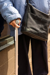 Elderly person with walking stick and handbag