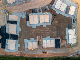 Excavator digging at construction site, building foundations in aerial view