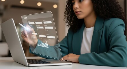 Young professional woman using a digital pen to fill out a form on a transparent laptop screen. She is wearing a green blazer and looking focused.