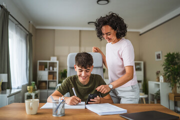 Fototapeta premium Mother and teenage boy do some homework together at home