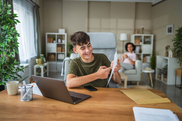 teenage boy talk on video call while his mom sit in the background